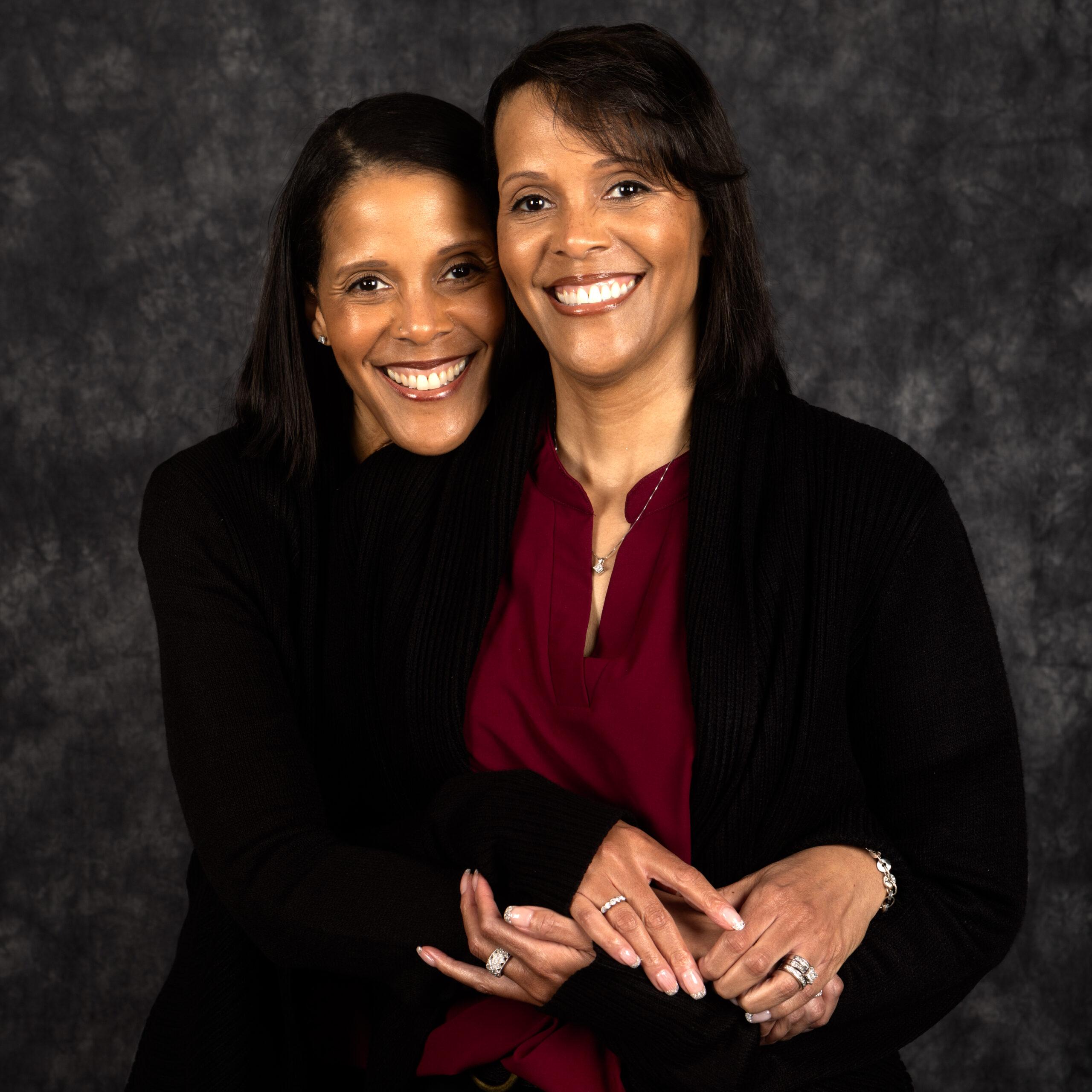 Twin sisters Joyce Malone and Jacintha Malone-Smith smile and embrace.