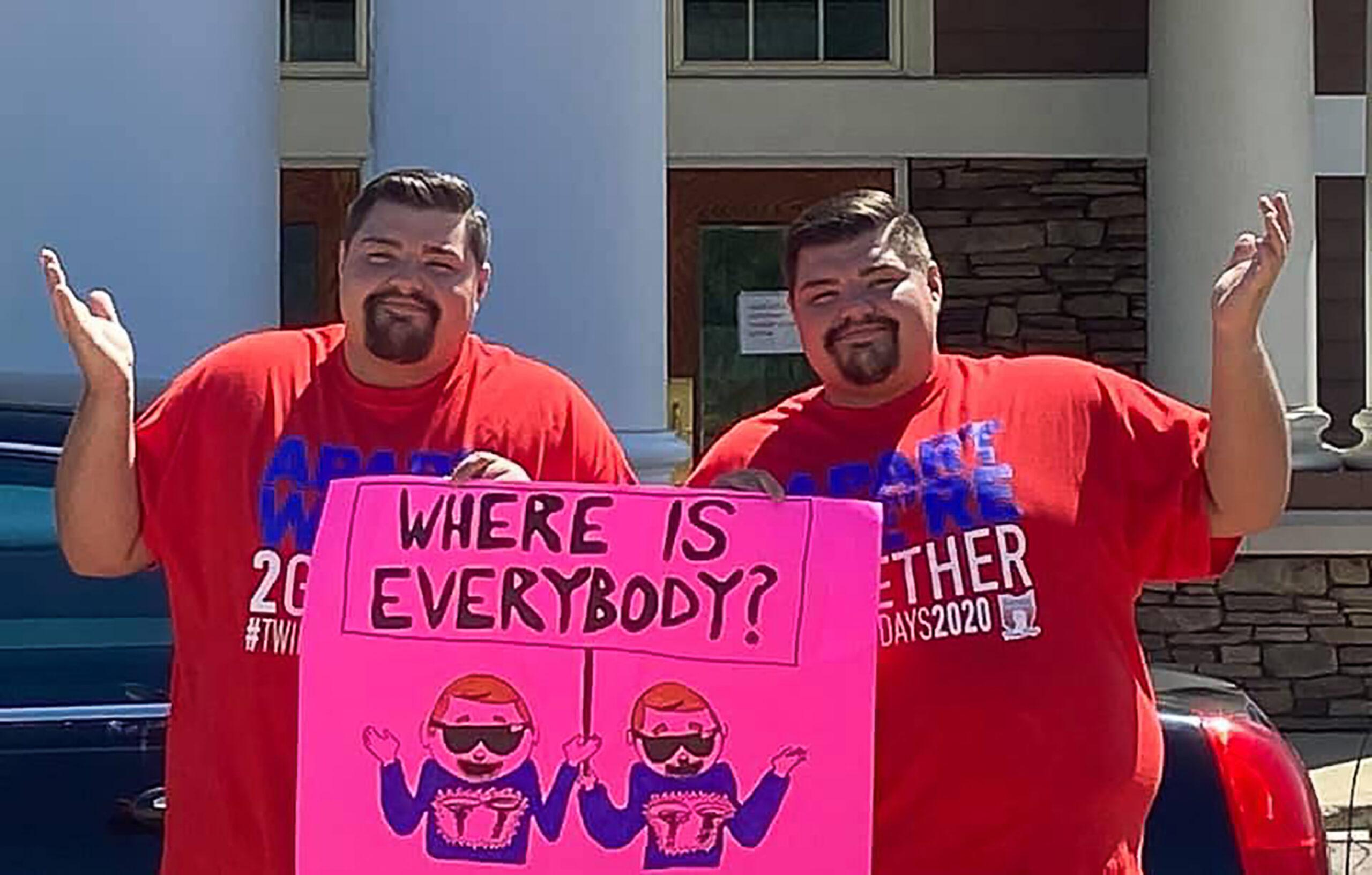 Twins Spencer and Skyler Nick pose with a sign that says “Where is everybody?” in Twinsburg during the 2020 Twins Days, which was remote-only.