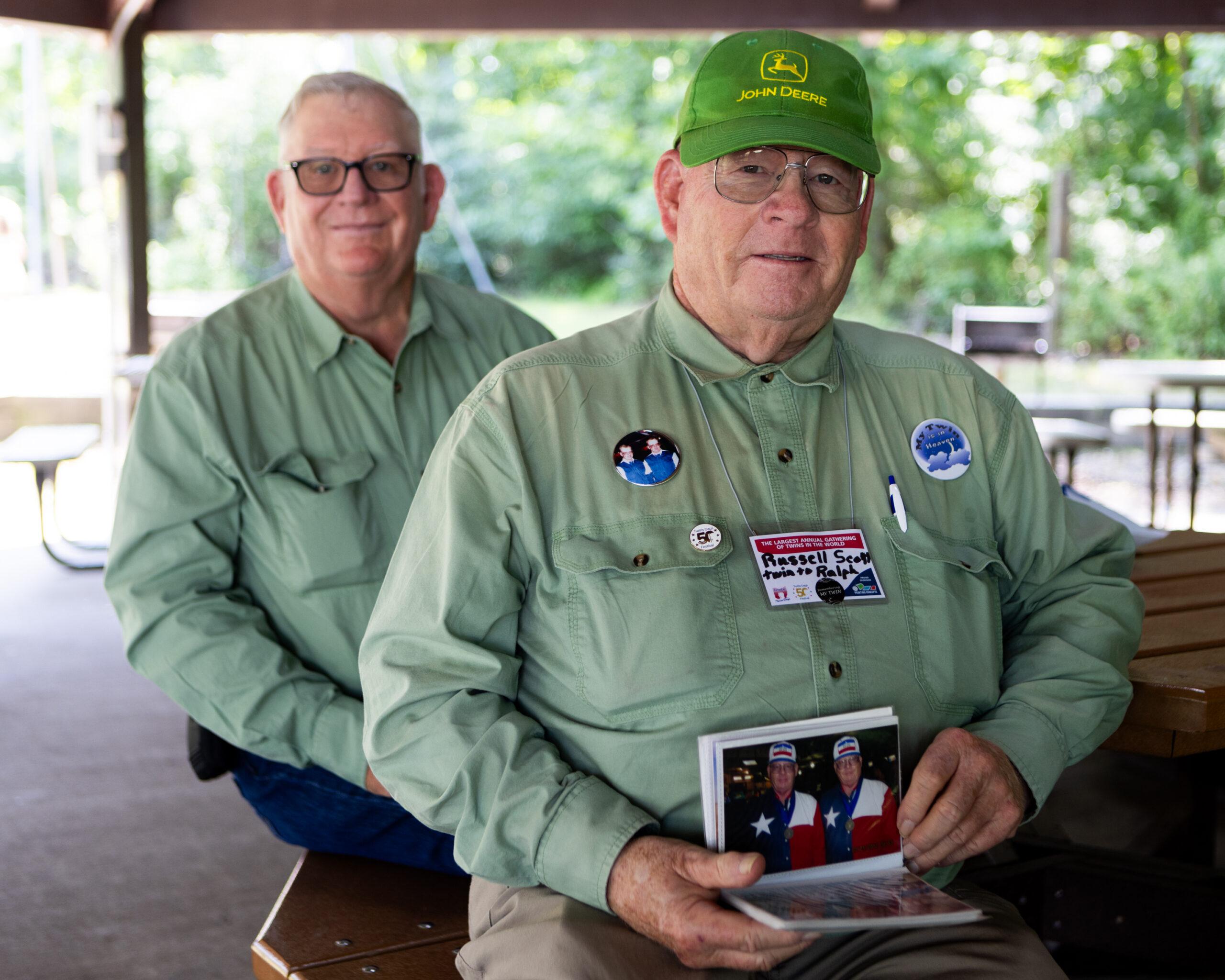 Russell Scott (right) holds of a photo album of himself with his late twin Ralph. His younger brother Stanley attends Twins Days with him for support.